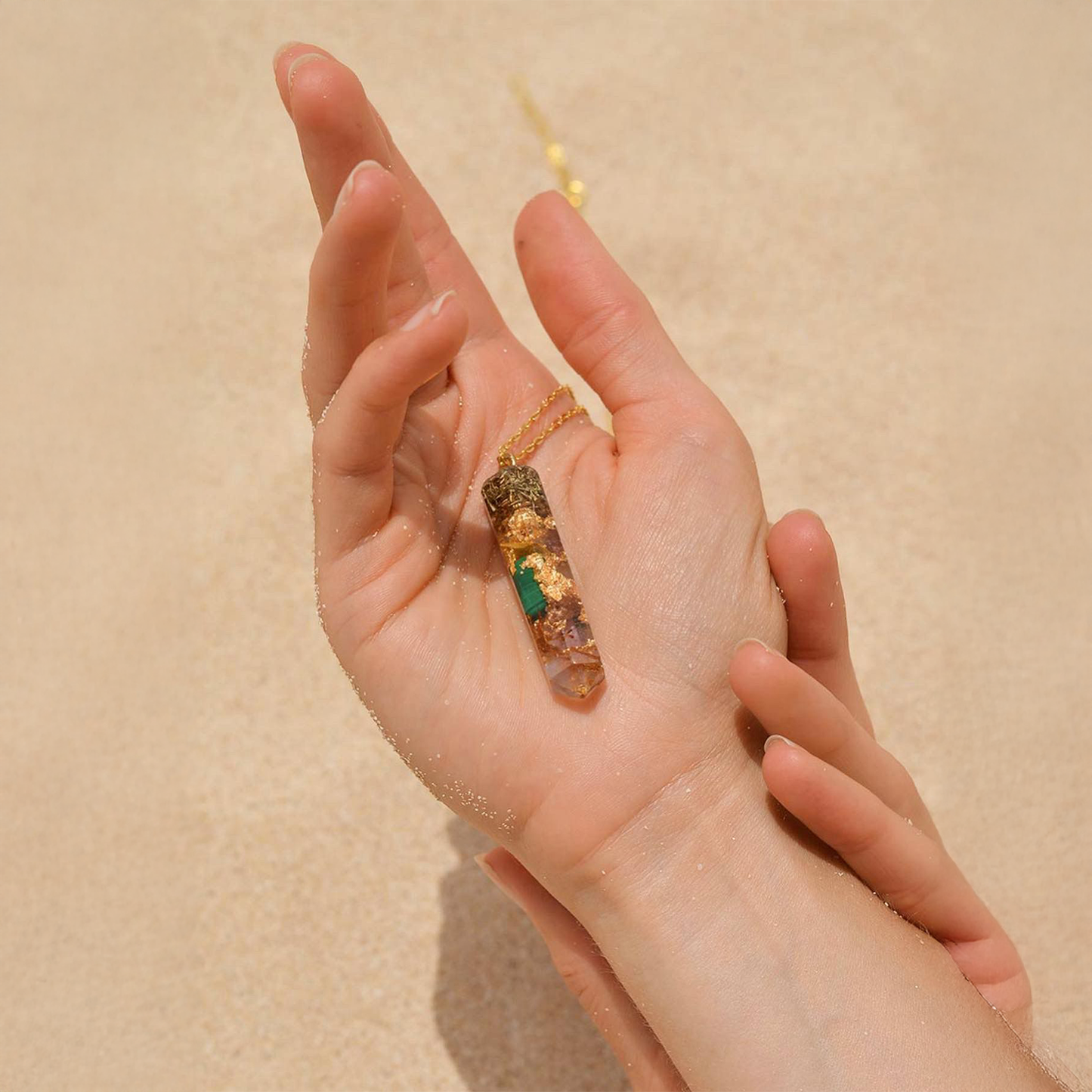 Hand holding a crystal with a beige background